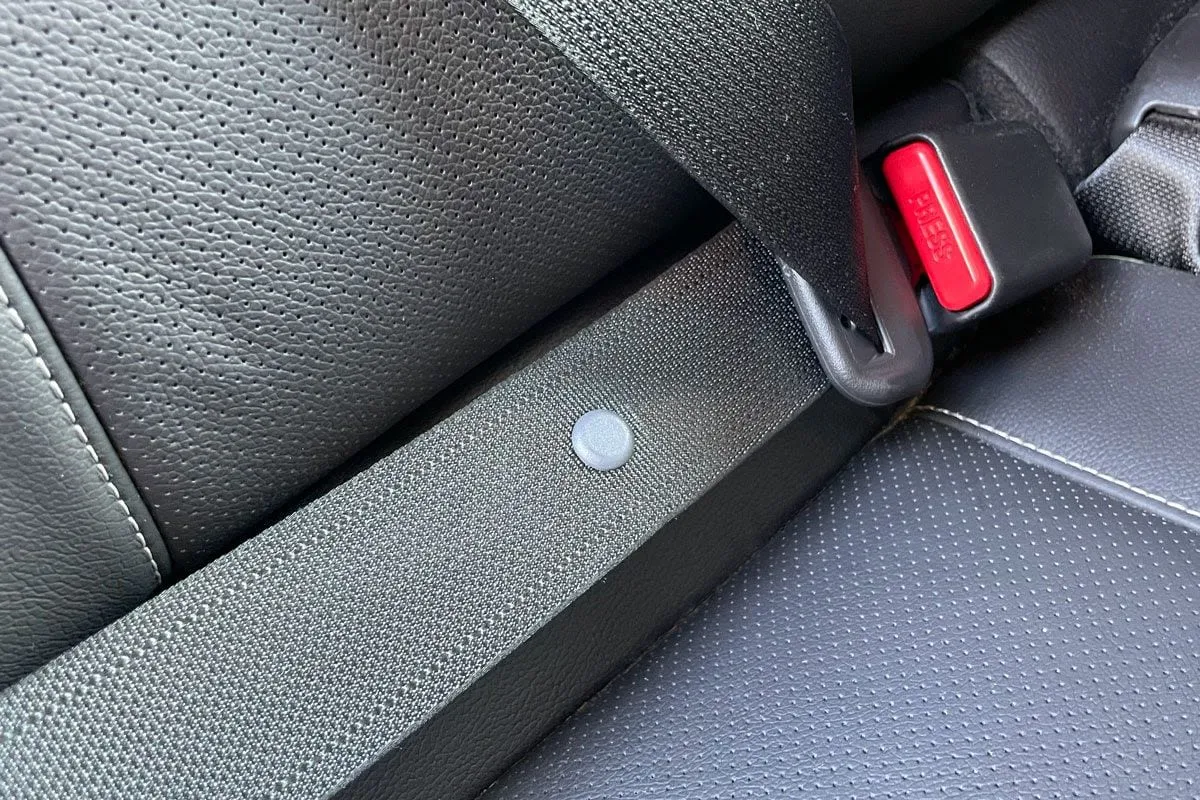 Explanation of the little plastic stop button on car seat belts for driver convenience and safety