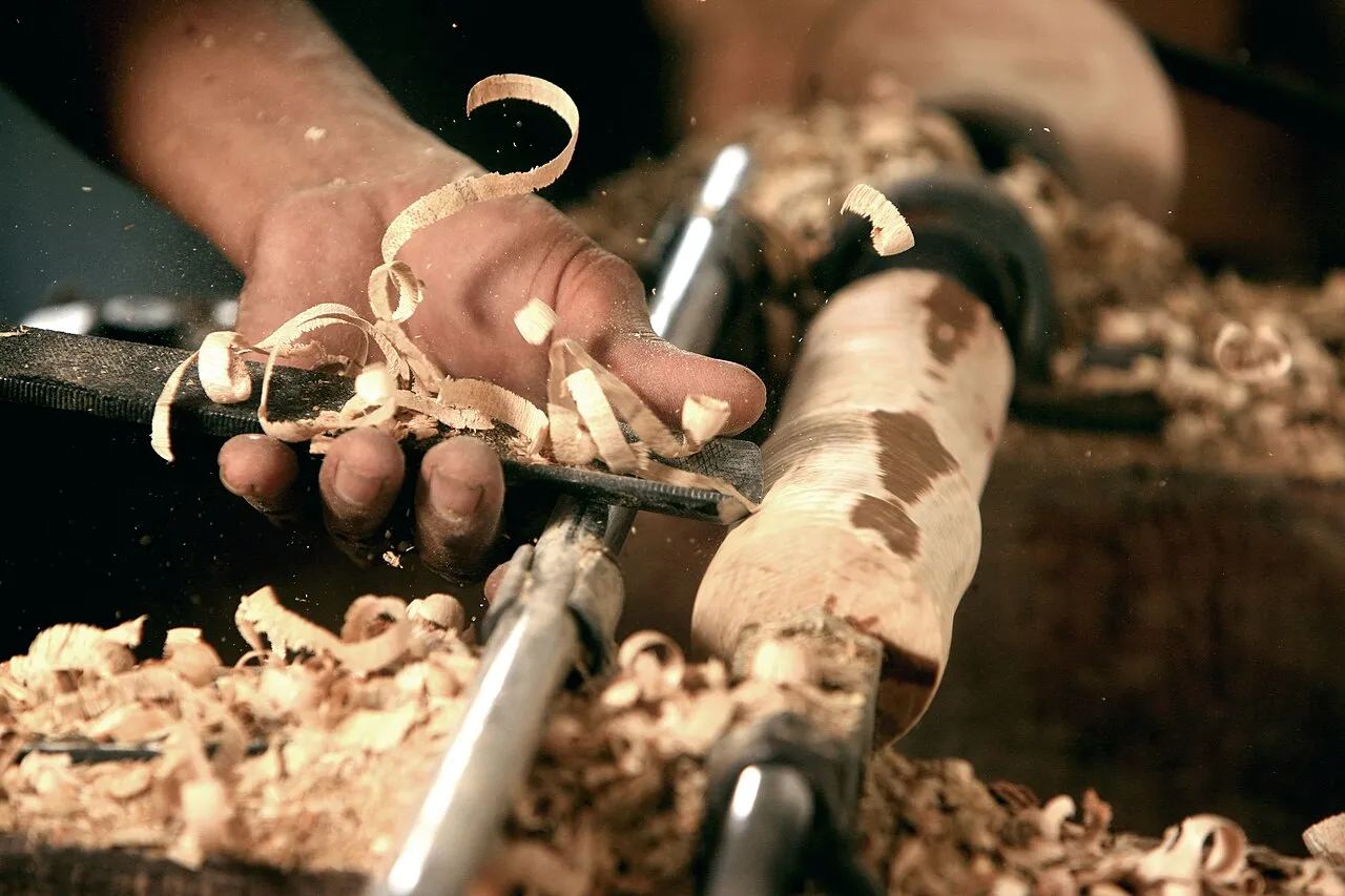 Woodturning artisan crafting symmetrical objects on a modern wood lathe using hand tools